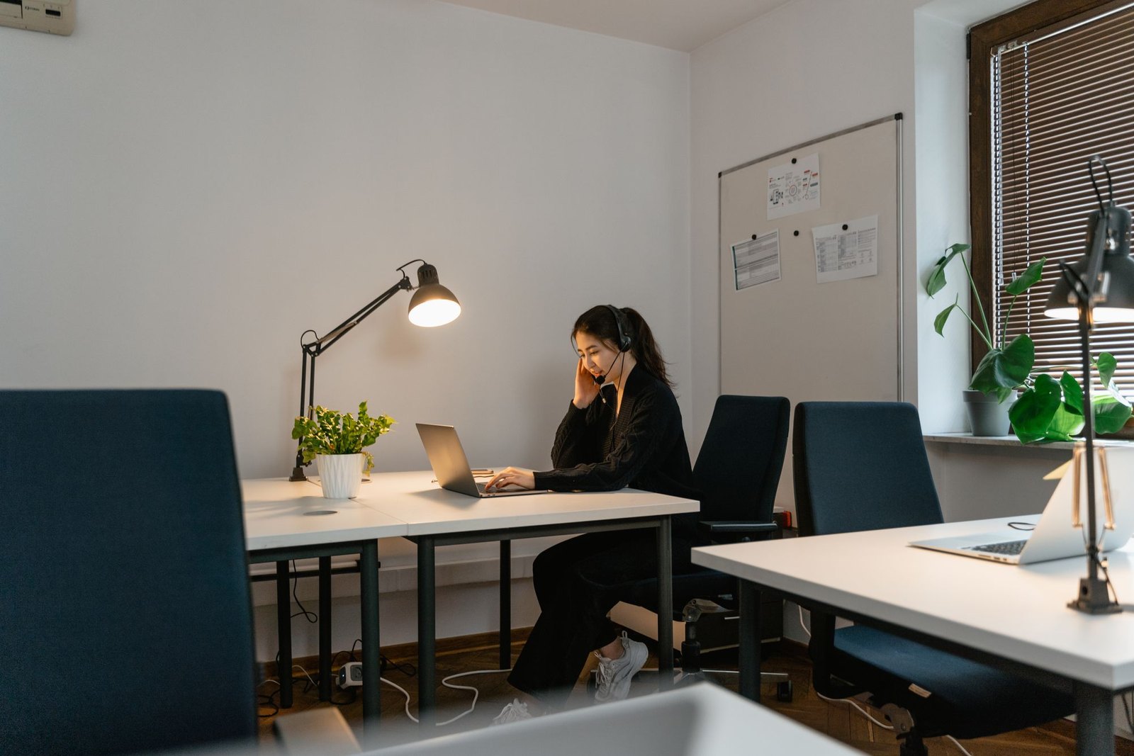 Customer care specialist with a headset following up with past customers at a laptop