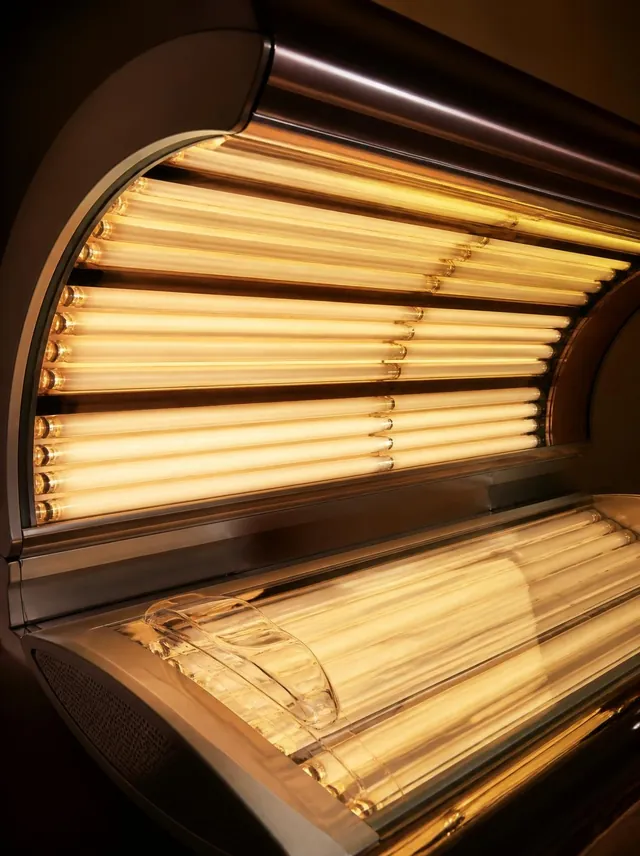 Glowing replacement lamp tubes inside an open modern tanning bed canopy
