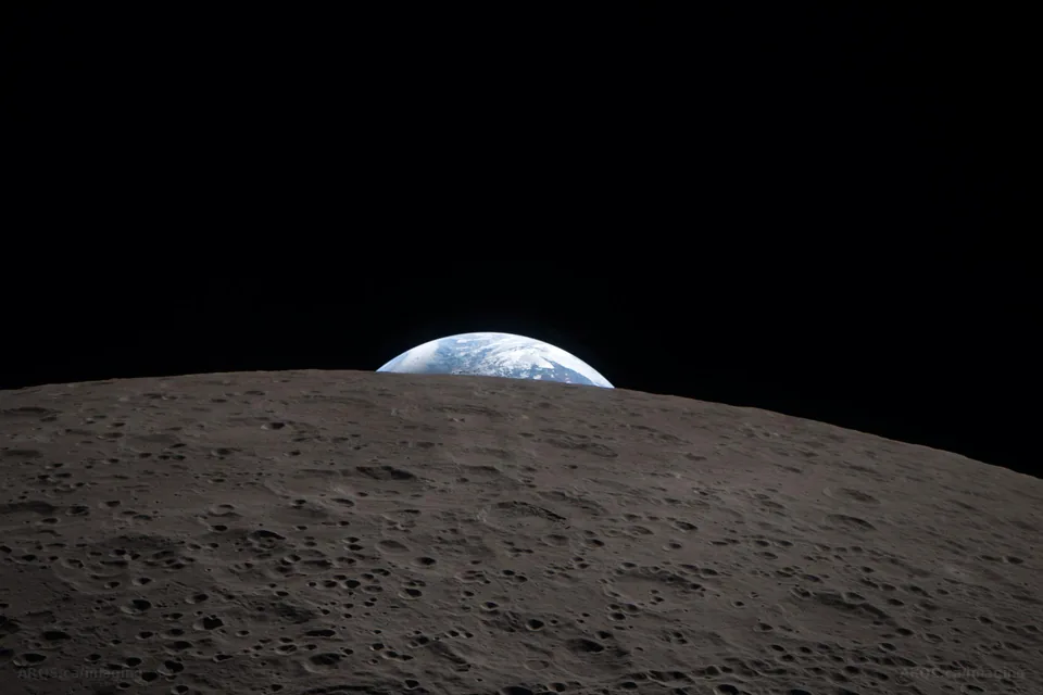 Earth setting behind the cratered far-side horizon of the Moon, photographed by the Artemis II crew from the Orion spacecraft