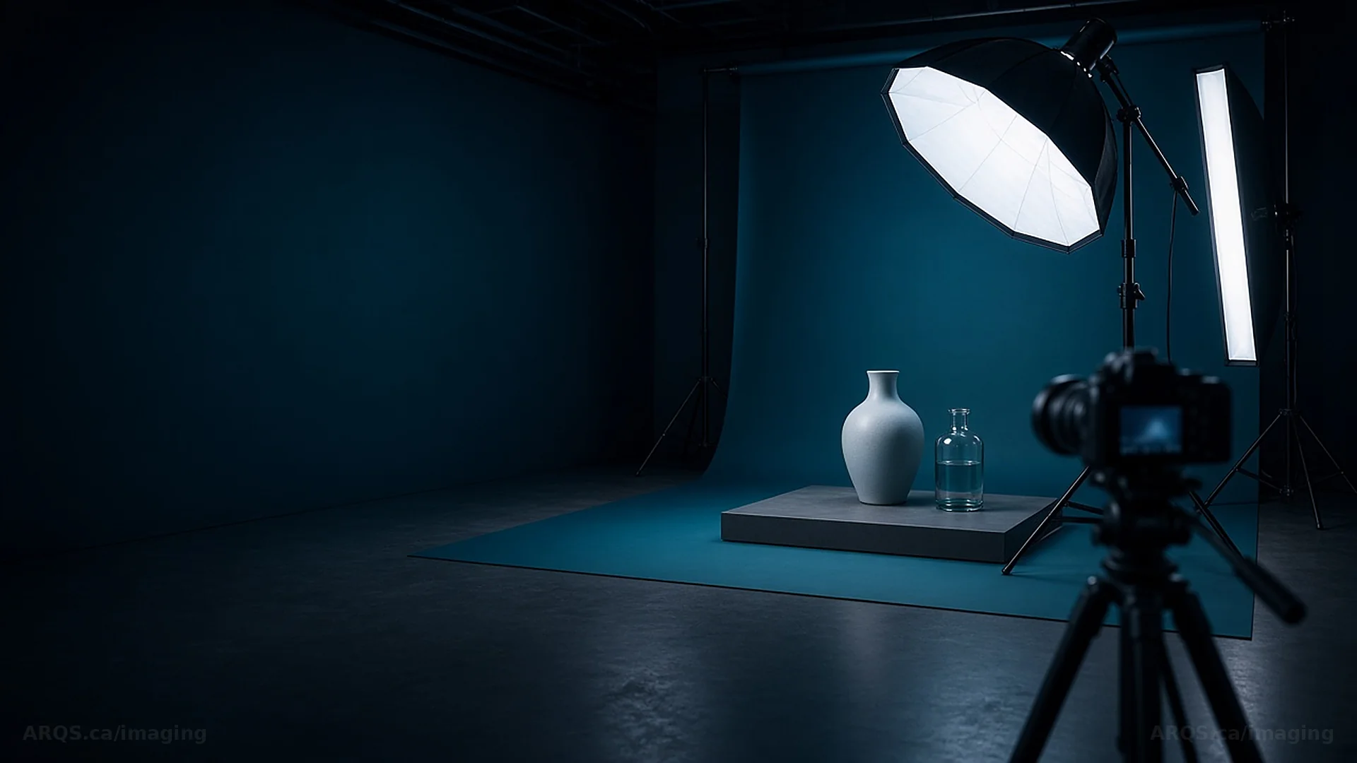 Empty product photography studio with a ceramic vase and glass bottle on a teal backdrop under a softbox