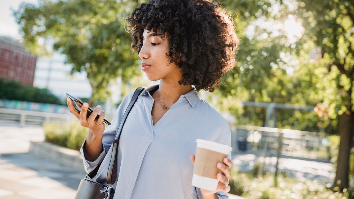 Resident checking her phone with a coffee before heading out