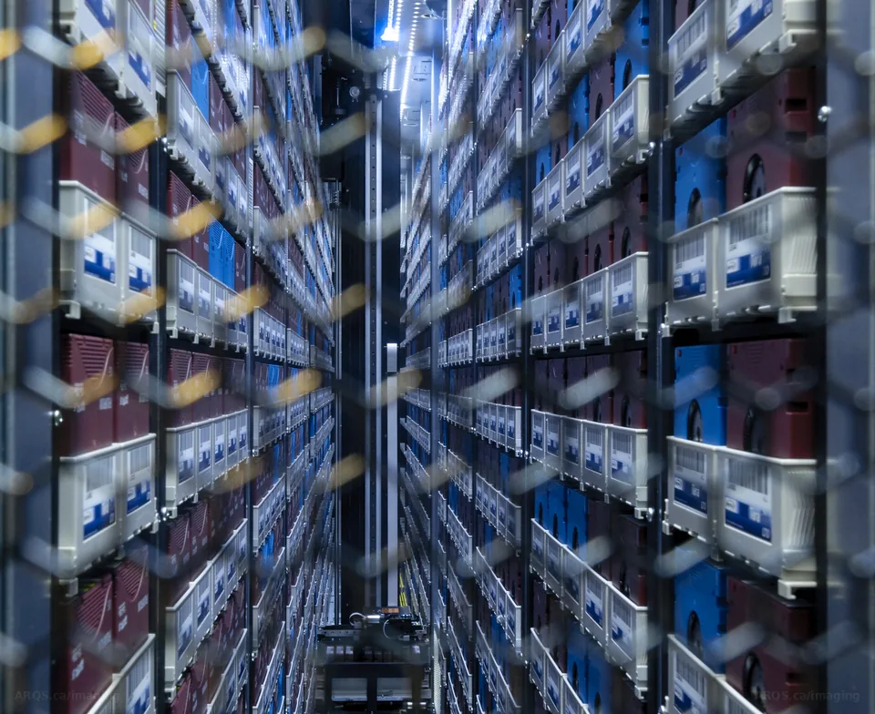 Looking down the aisle of a robotic tape library, thousands of cartridges stacked floor to ceiling