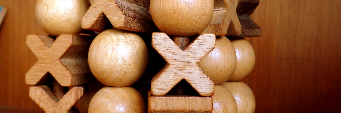 A wooden noughts-and-crosses puzzle with carved X pieces and round O beads