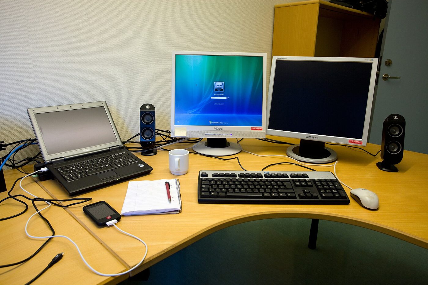A desk with a laptop, two monitors and a keyboard