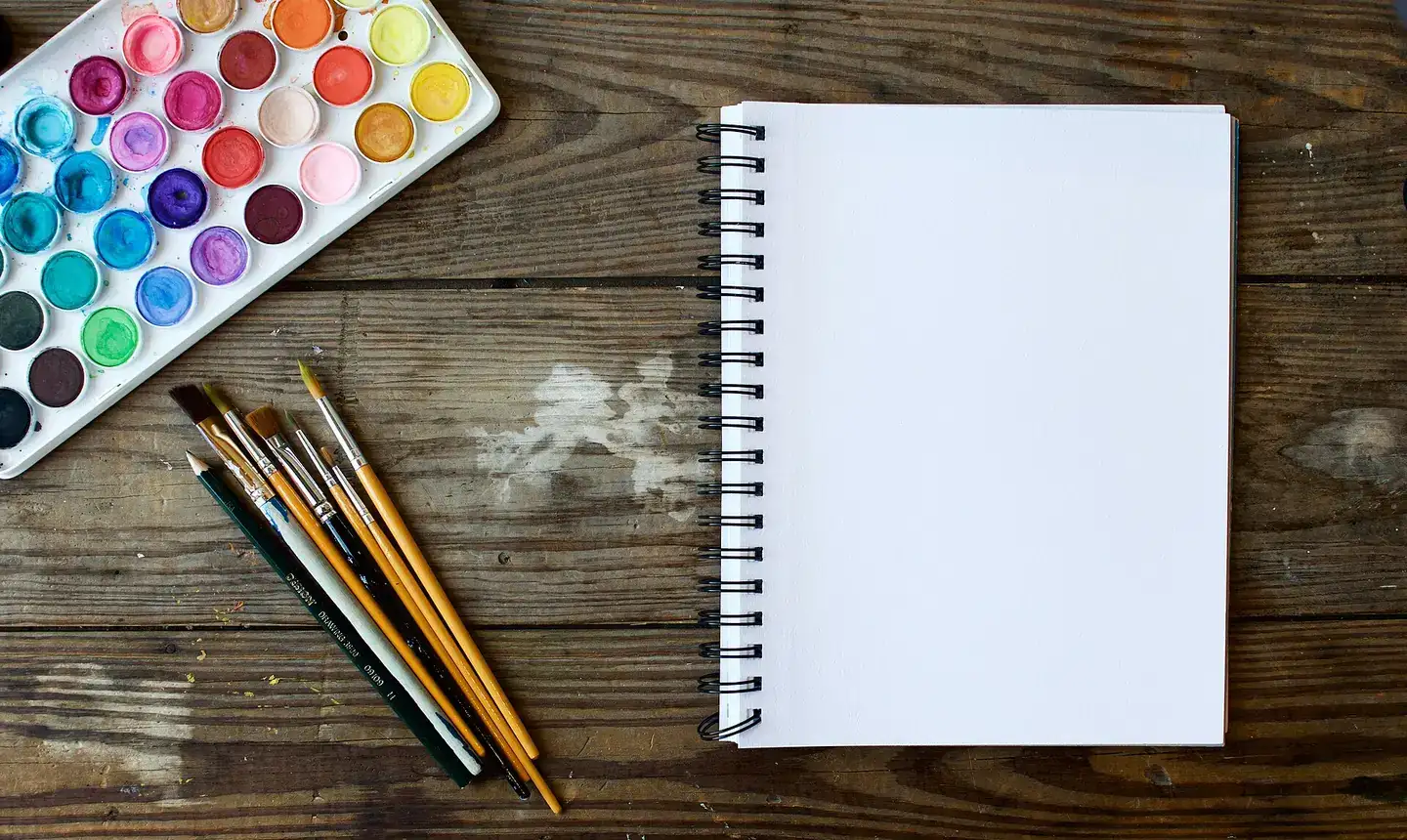 A notebook with paint brushes and color palette