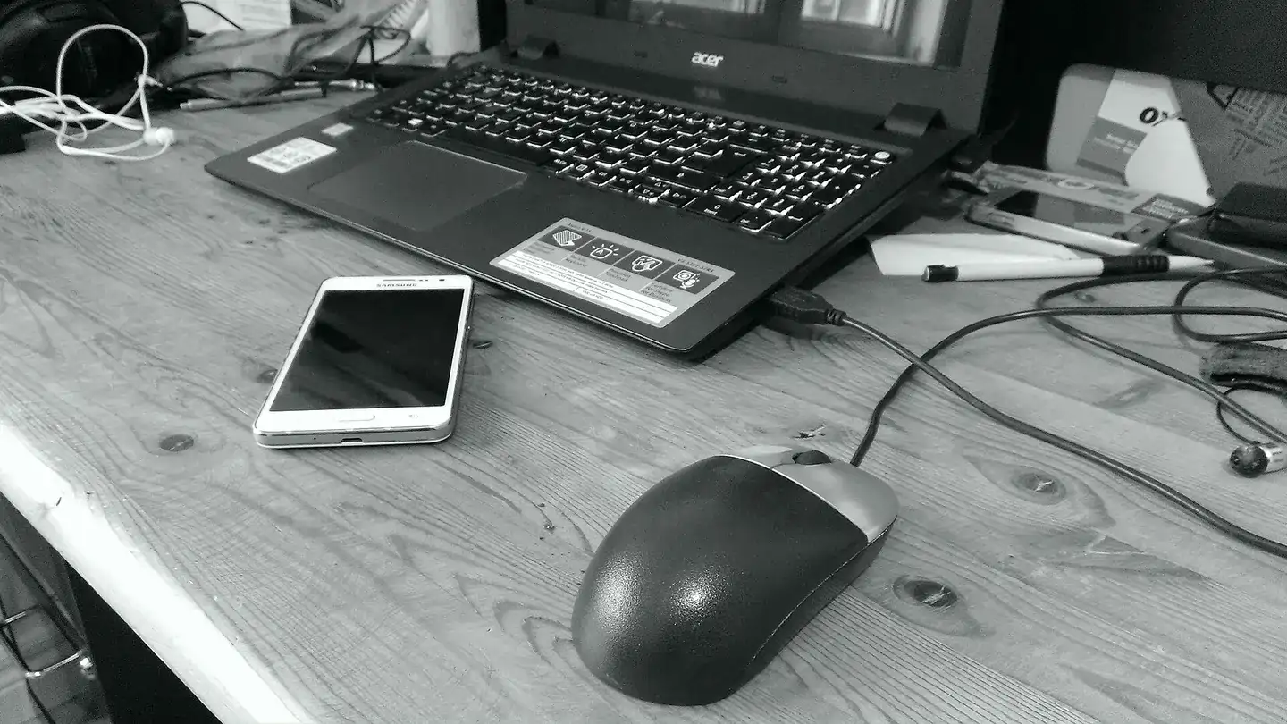 A laptop computer along with a telephone and a computer mouse setting on a desk