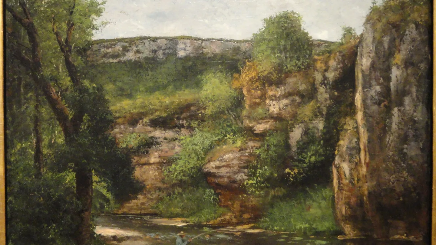 A framed landscape painting of a forest gorge in a gallery