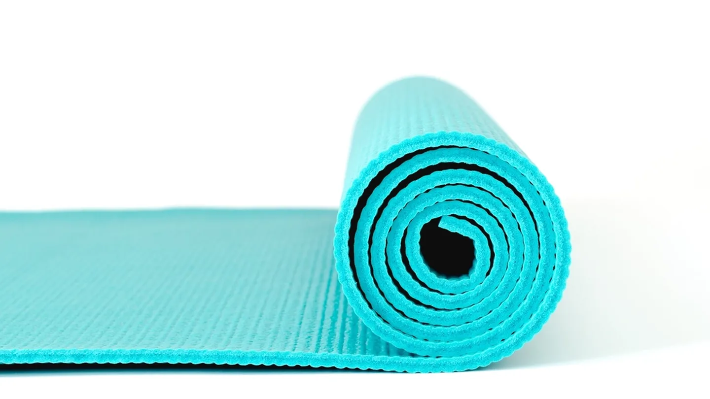 A rolled turquoise yoga mat ready for home practice