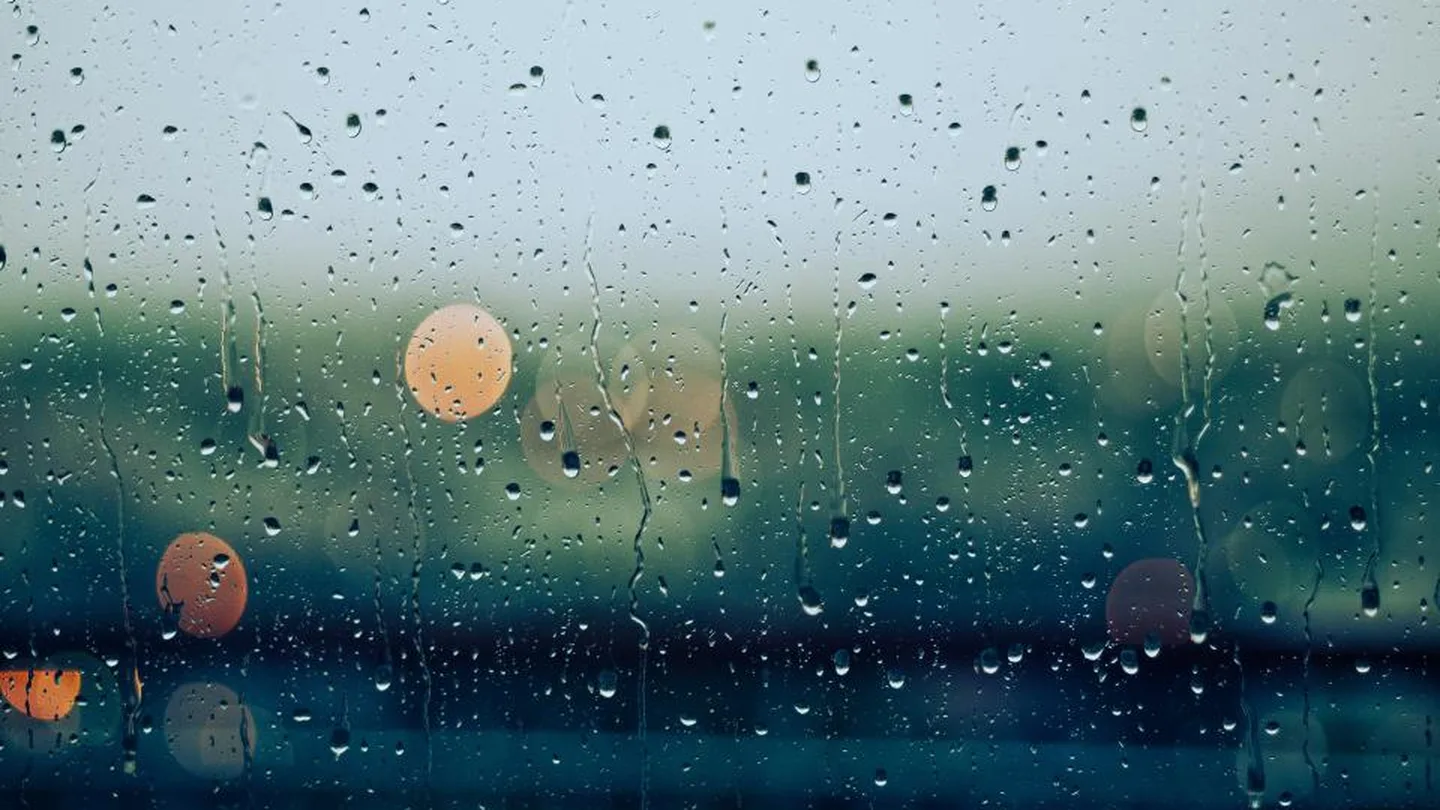 Raindrops on a window with soft city lights behind